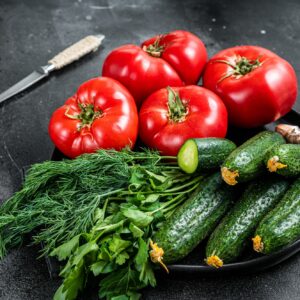 Paradajky, uhorky, kôpor, petržlenová vňať a cesnak na tmavom tanieri