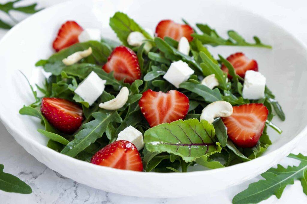vitamin salad of strawberry with arugula spinach leaves feta cheese and cashew nuts
